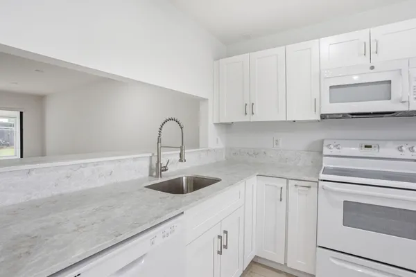 a kitchen with white cabinets and sink