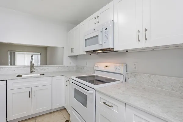 a kitchen with white cabinets and white appliances
