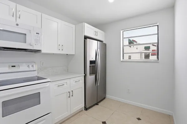 a kitchen with white cabinets and white appliances