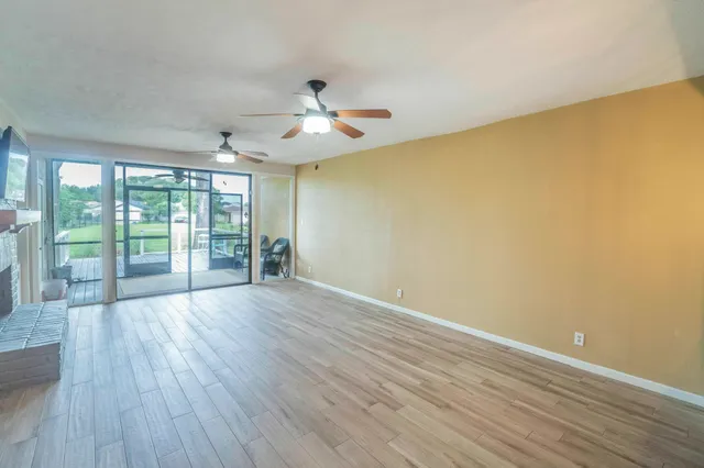 an empty room with wooden floor ceiling fan and windows