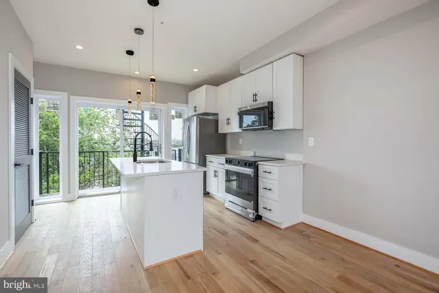 a kitchen with a sink a counter top space stainless steel appliances and a large window