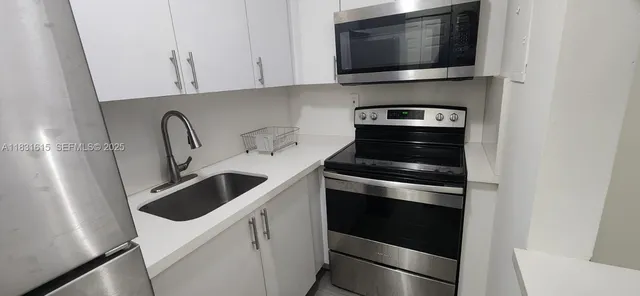 a kitchen with white cabinets and stainless steel appliances