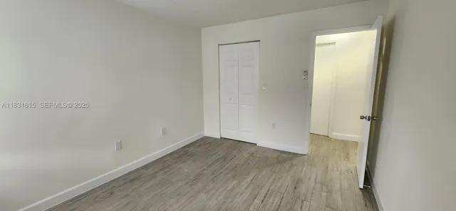 a view of a refrigerator in kitchen and an empty room