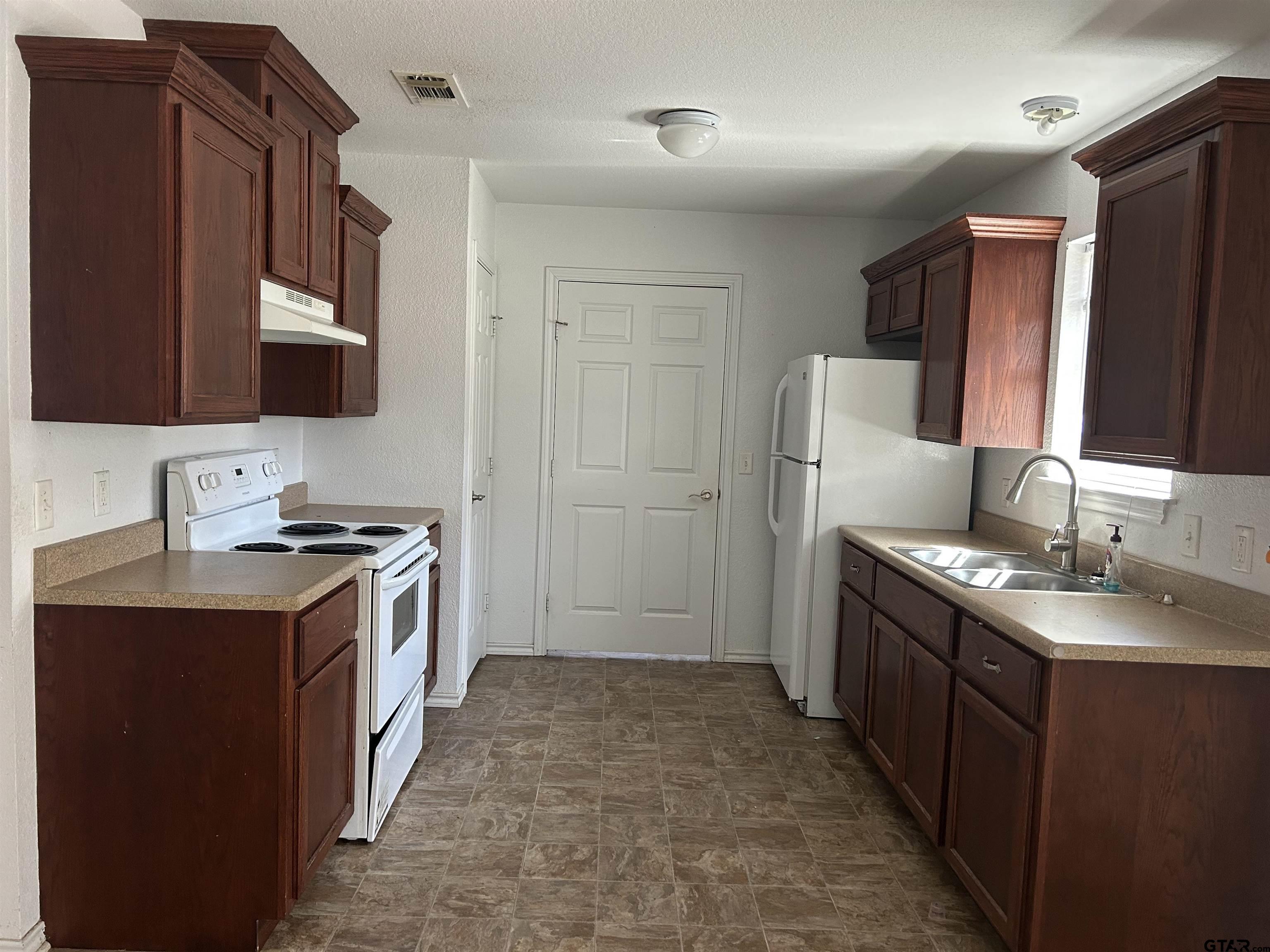 803 Sims Avenue Jacksonville, TX 75766 - Photo 4 of 18 a kitchen with a sink stove and refrigerator