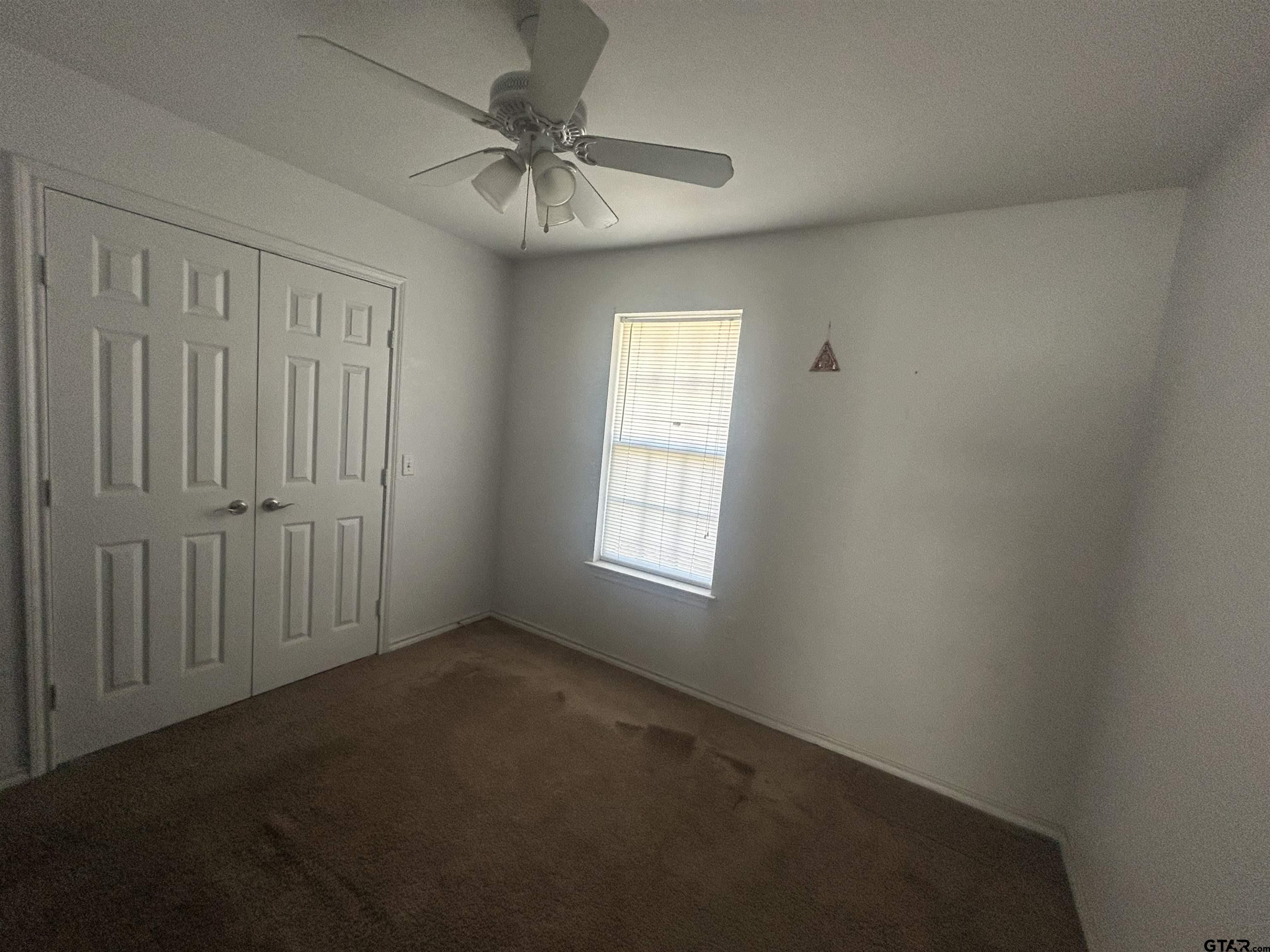 803 Sims Avenue Jacksonville, TX 75766 - Photo 10 of 18 an empty room with a chandelier fan and windows