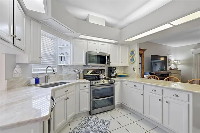 a kitchen with stainless steel appliances granite countertop a dining table chairs refrigerator and sink