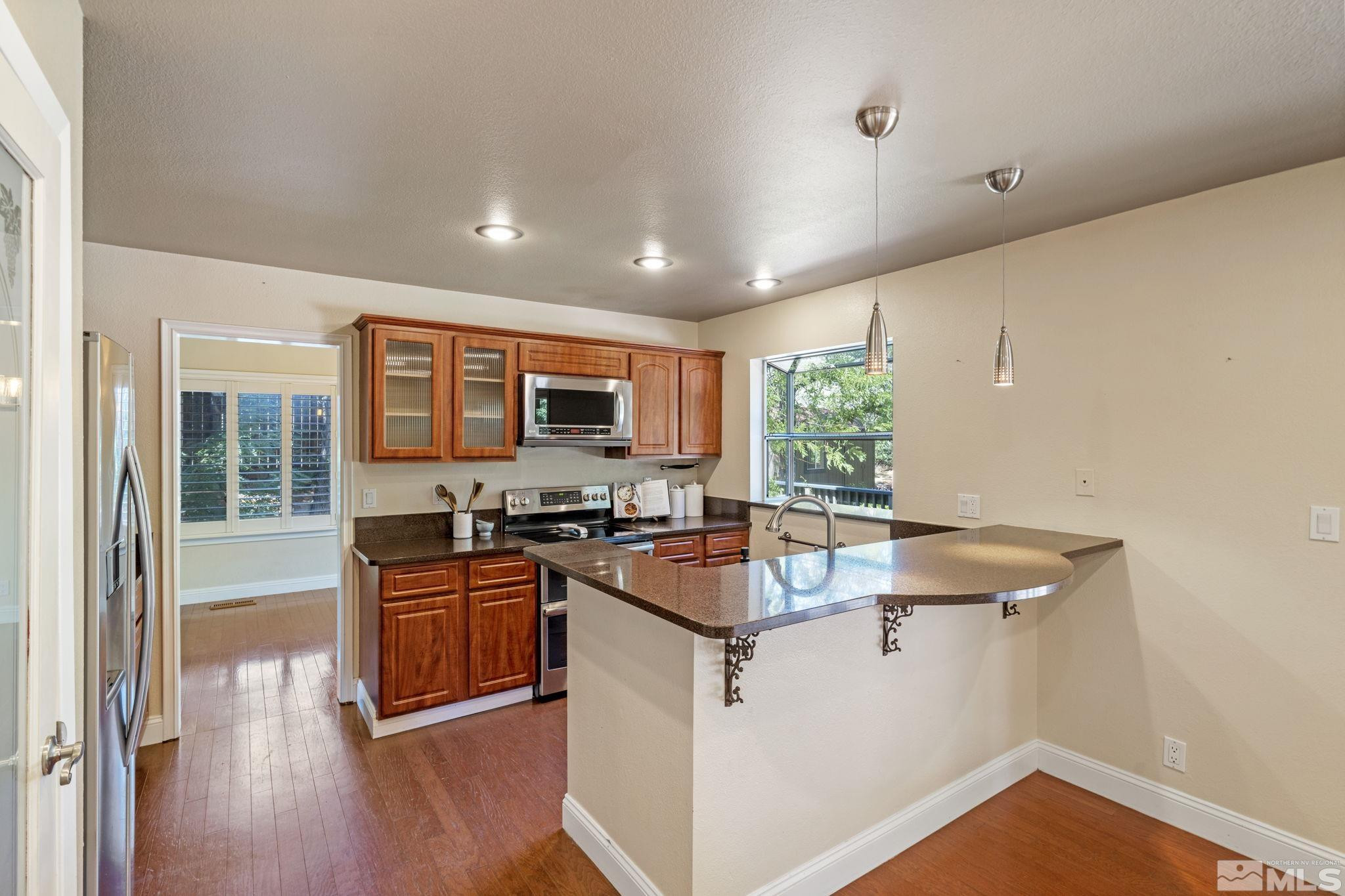 2197 Solitude Drive Reno, NV 89511 - Photo 17 of 40 a kitchen with stainless steel appliances granite countertop a stove top oven a sink a refrigerator white cabinets and wooden floor