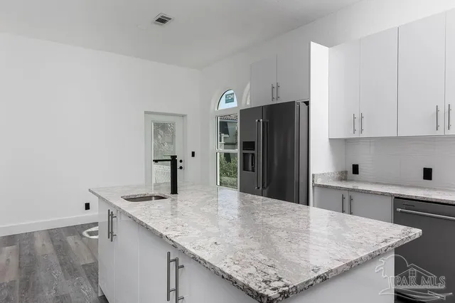 a kitchen with granite countertop a refrigerator and a sink