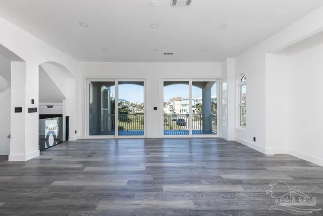 a view of an empty room with window and wooden floor