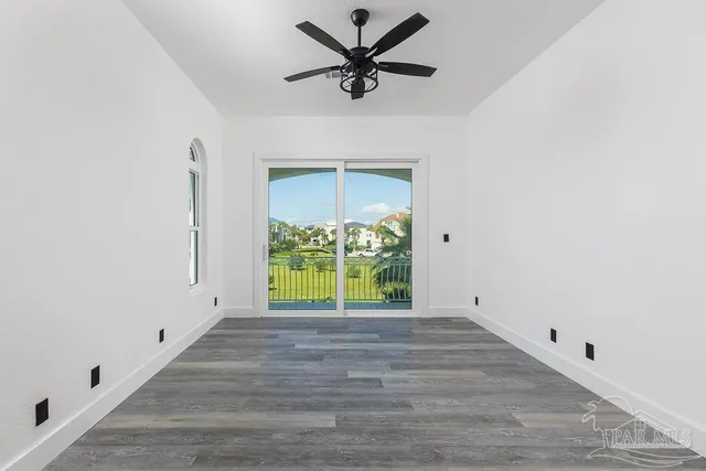 a view of an empty room with a window and a kitchen