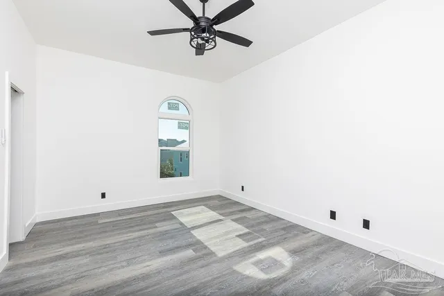 an empty room with a window and a ceiling fan