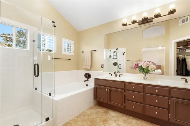 a bathroom with a tub sink double vanity granite tub shower and mirror
