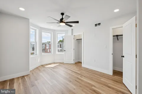 a view of empty room with wooden floor and fan