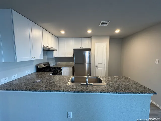a kitchen with kitchen island a counter top space cabinets and stainless steel appliances