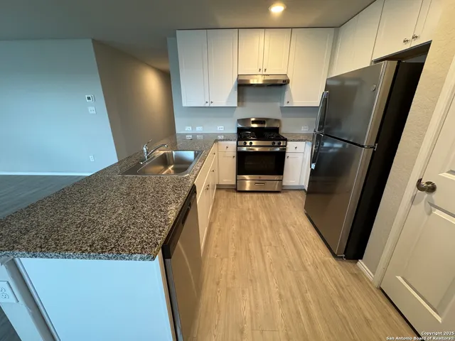 a kitchen with stainless steel appliances granite countertop a refrigerator a stove and a sink