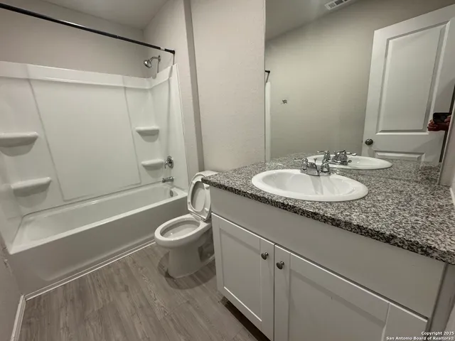 a bathroom with a granite countertop sink toilet and shower