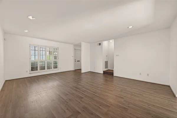 a view of an empty room with wooden floor and windows