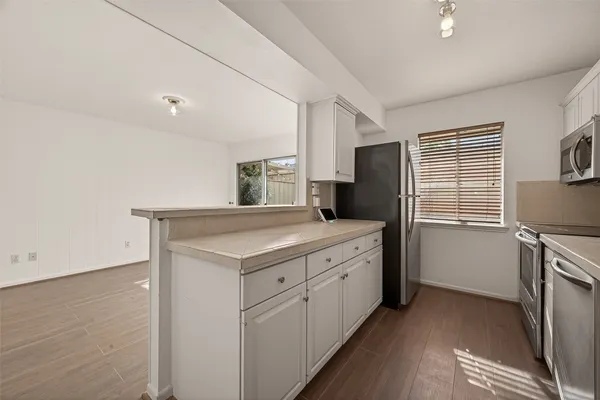 a kitchen with granite countertop a refrigerator a sink a stove and wooden floor