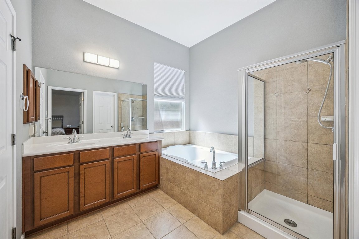1427 Gorham Street Austin, TX 78758 - Photo 13 of 20 Full bath featuring a stall shower, a garden tub, ensuite bath, light tile patterned floors, and double vanity