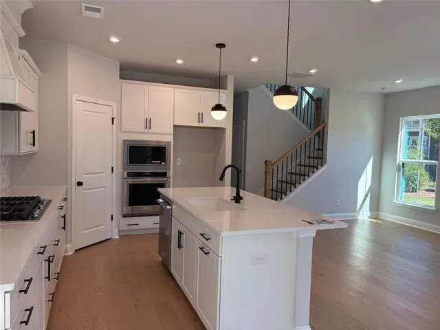 a kitchen with stainless steel appliances kitchen island a white stove top oven a sink a refrigerator and a dining table with wooden floor