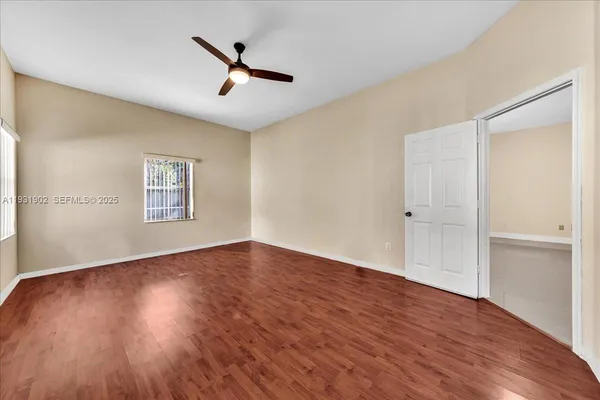 an empty room with wooden floor chandelier fan and closet area