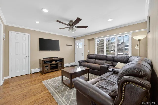 a living room with furniture a ceiling fan and a flat screen tv