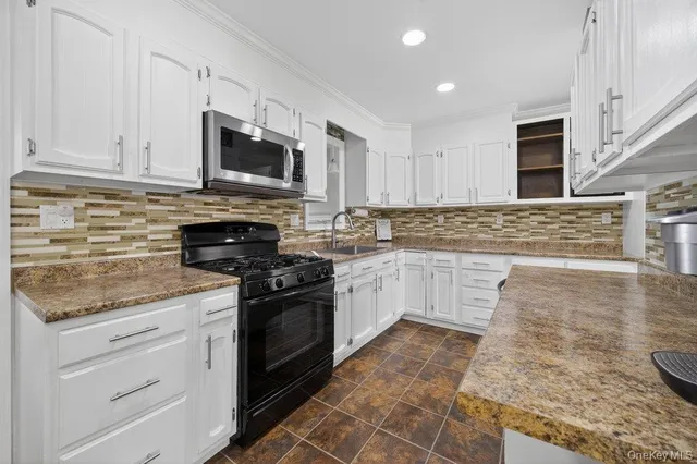 a kitchen with stainless steel appliances granite countertop a stove a sink and a microwave