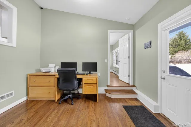 a view of a workspace with wooden floor and furniture