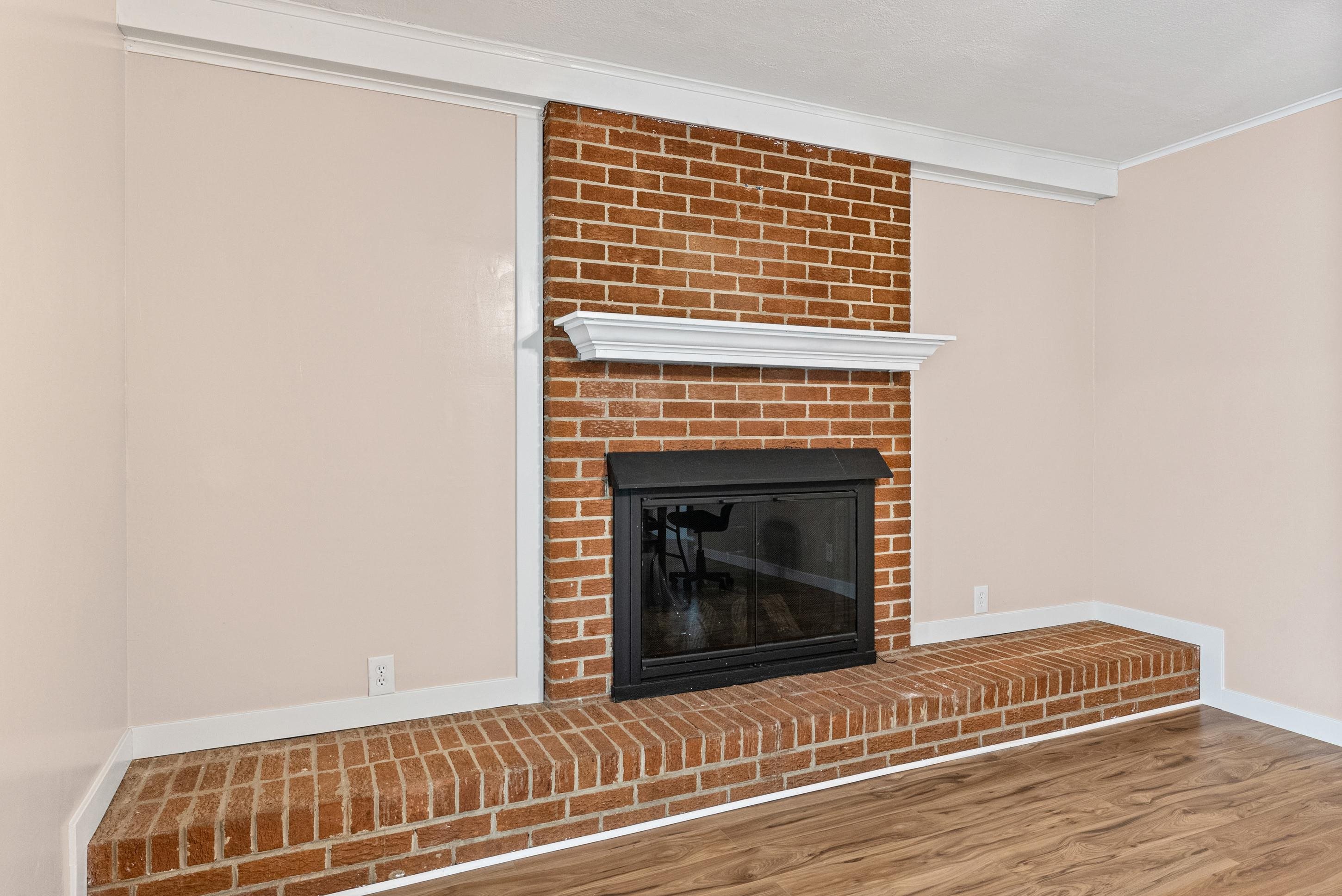 779 Strickland Road Coldwater, MS 38618 - Photo 18 of 40 Brick fireplace with a white mantel, black firebox, and a brick hearth