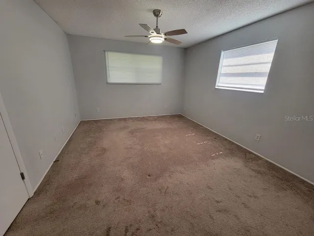 an empty room with windows and ceiling fan