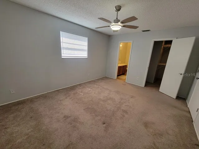 an empty room with windows and fan