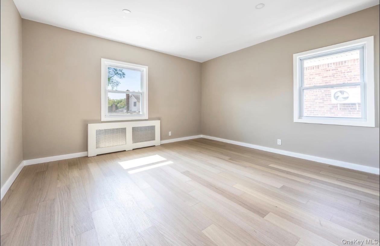 208-12 53rd Avenue Queens, NY 11364 - Photo 8 of 11 a view of an empty room with a window and wooden floor