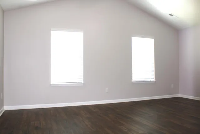 an empty room with wooden floor and a window