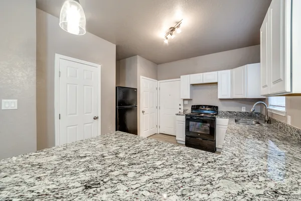 a kitchen with granite countertop a refrigerator and a stove top oven