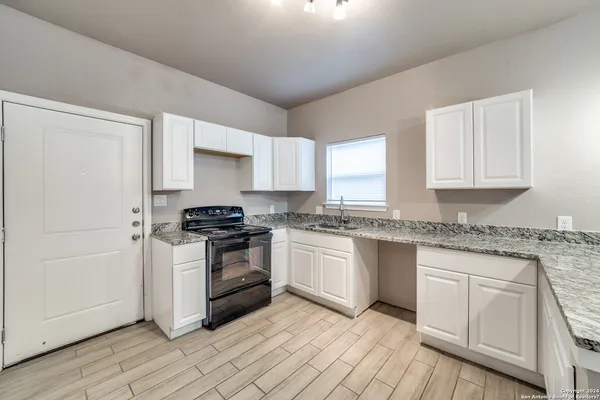 a kitchen with granite countertop white cabinets and white appliances