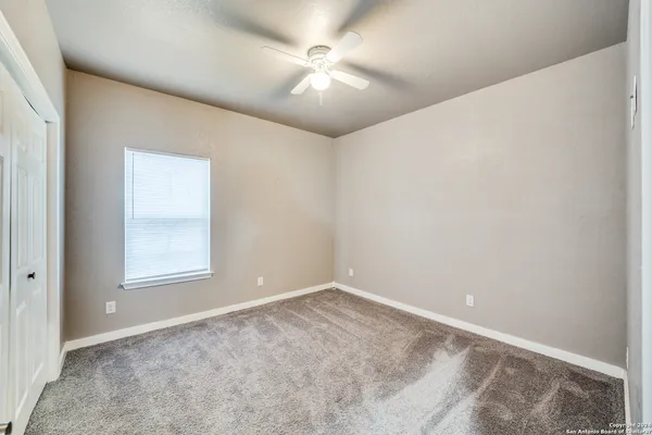 an empty room with windows and fan