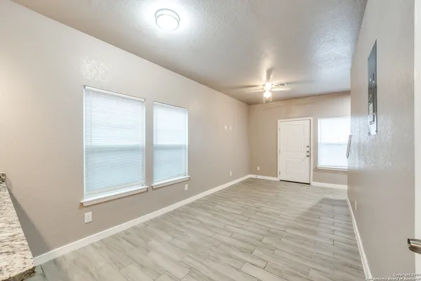 a view of an empty room with window and wooden floor