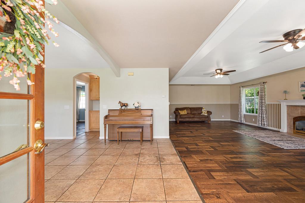 6181 Lambert Lane El Dorado, CA 95623 - Photo 15 of 68 living area featuring arched walkways, tile patterned flooring, ceiling fan, beam ceiling, and a fireplace