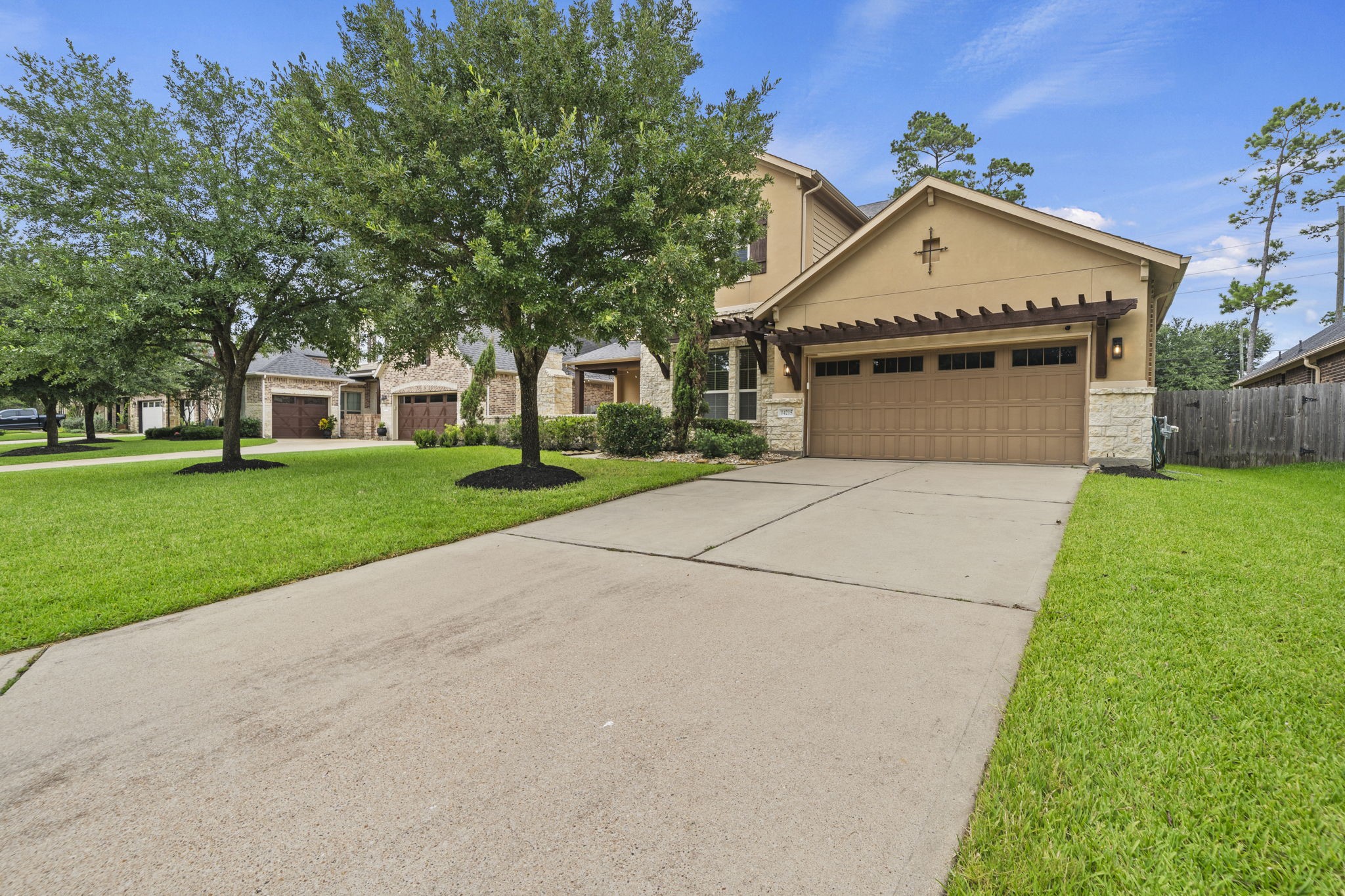 14215 Spindle Arbor Road Cypress, TX 77429 - Photo 45 of 47 This photo showcases a charming two-story home with a spacious driveway leading to a two-car garage. The well-maintained front yard features lush green grass and mature trees, offering a welcoming and serene environment.
