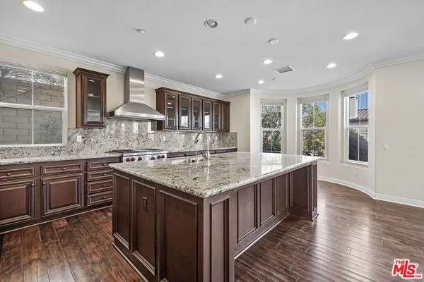a kitchen with stainless steel appliances granite countertop a sink a stove and a wooden floors
