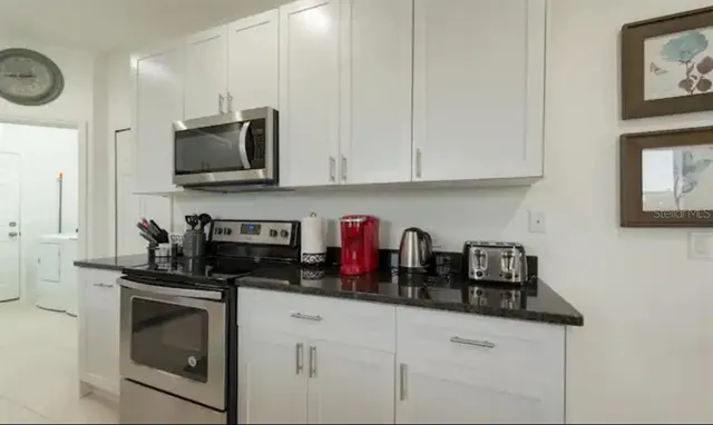 a kitchen with white cabinets and black appliances