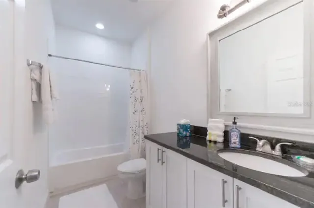 a bathroom with a granite countertop sink toilet and shower