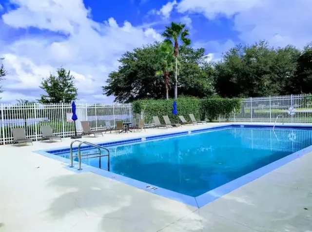 a view of a swimming pool with a patio and a yard