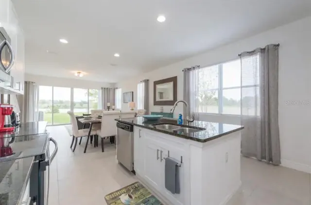 a dining hall with granite countertop a stove a sink a dining table and chairs