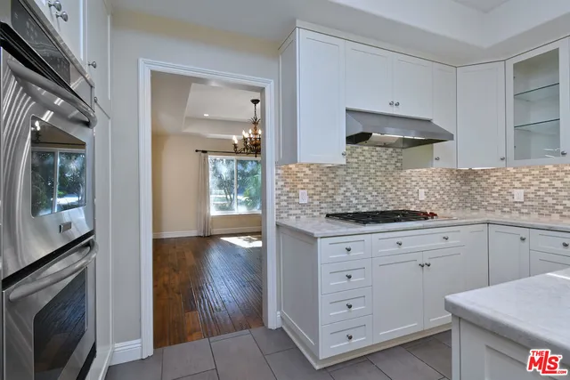 a kitchen with granite countertop white cabinets and stainless steel appliances