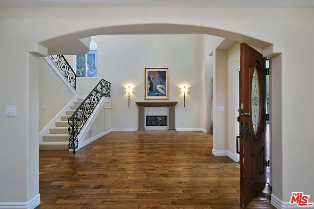 a view of an empty room with wooden floor and a chandelier
