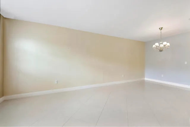 a view of an empty room with a chandelier fan