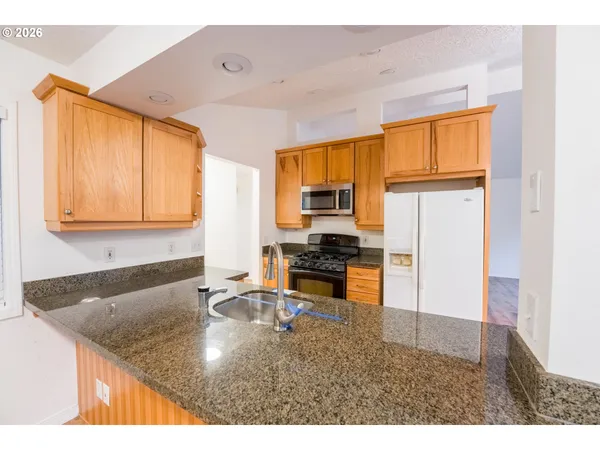 a kitchen with stainless steel appliances granite countertop a sink refrigerator and cabinets