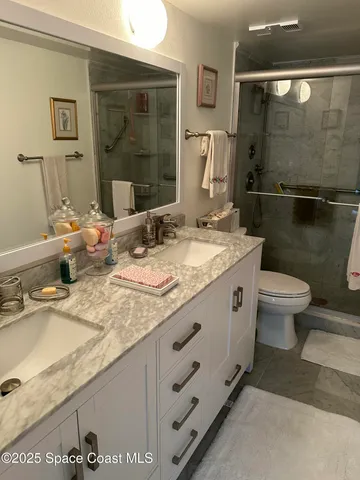 a bathroom with a granite countertop sink a toilet and shower