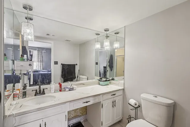 a bathroom with a double vanity sink mirror and toilet